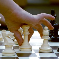 photo of hand with chess piece