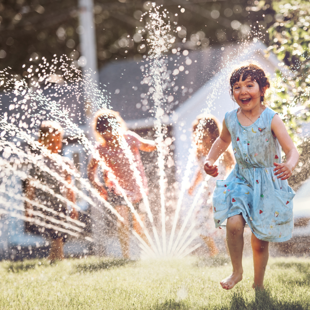 photo of kids running through sprinkler